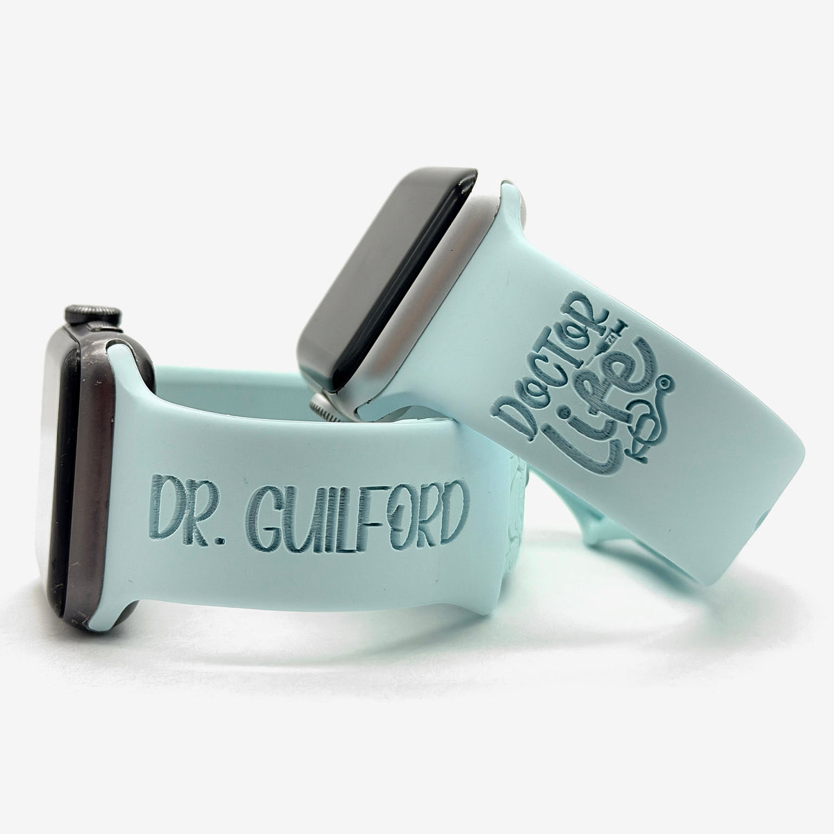 Ice blue Doctor watch band for Apple Watch engraved with the Doctor Life design, shown with a band engraved with the name Dr. Guilford