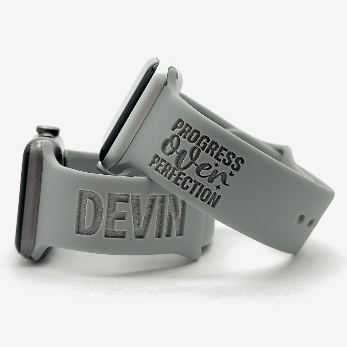 Grey Progress Over Perfection watch band for Apple Watch engraved with the Progress Over Perfection Bold design, shown with a band engraved with the name Devin
