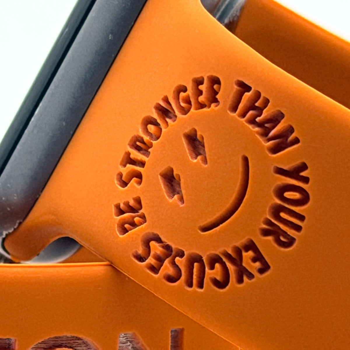 Engraving detail of the Be Stronger Than Your Excuses design on a rust watch band for Apple Watch