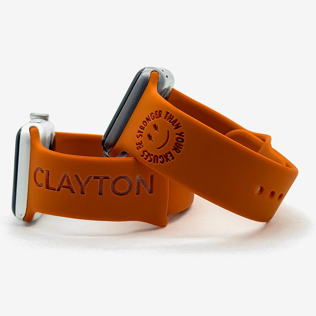 Rust watch band for Apple Watch engraved with Be Stronger Than Your Excuses around a smiley face, shown with a band engraved with the name Clayton
