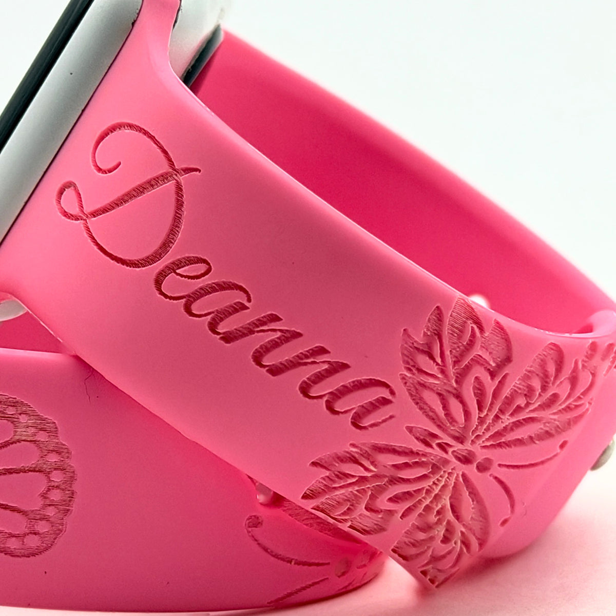 Close-up of a custom name and butterfly engraving on a pink silicone watch band for Apple Watch