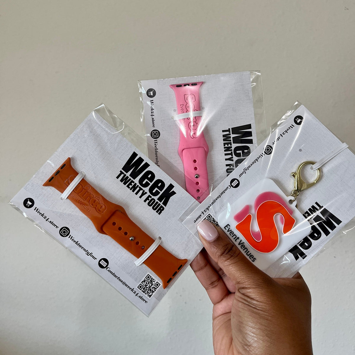 Custom logo engraved watch band for Apple Watchs in rust and pink with a matching logo keychain, packaged on Week Twenty Four cards