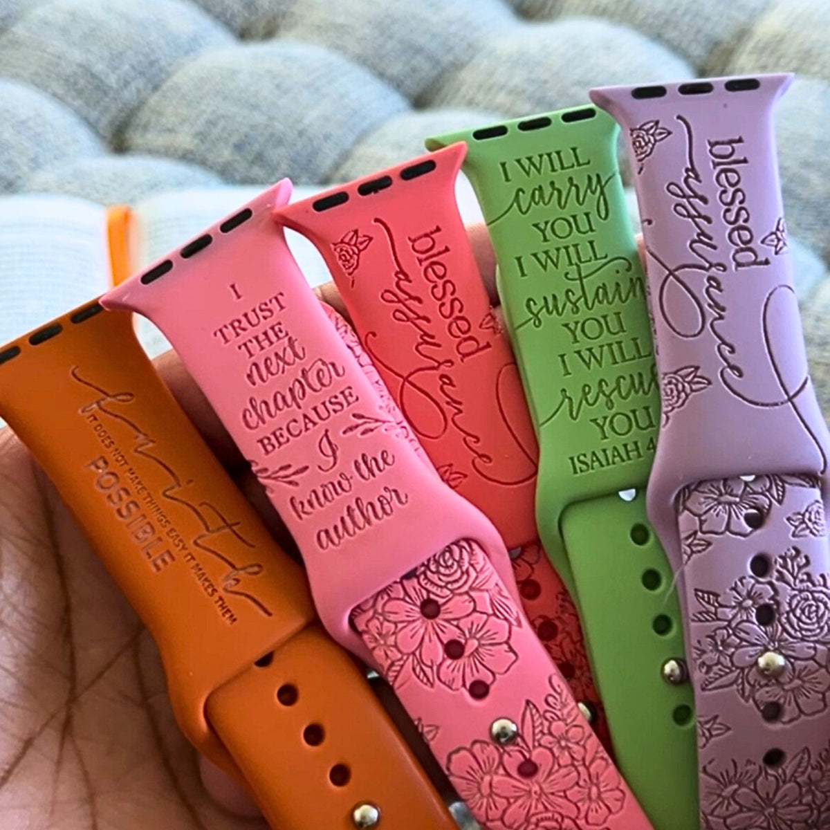 Hand holding five faith engraved watch band for Apple Watchs in rust, pink, coral, green and lavender