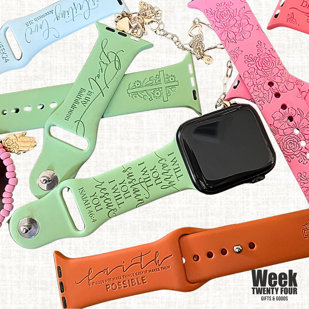 Flat lay of faith engraved watch band for Apple Watchs in green, pink and rust on a light background