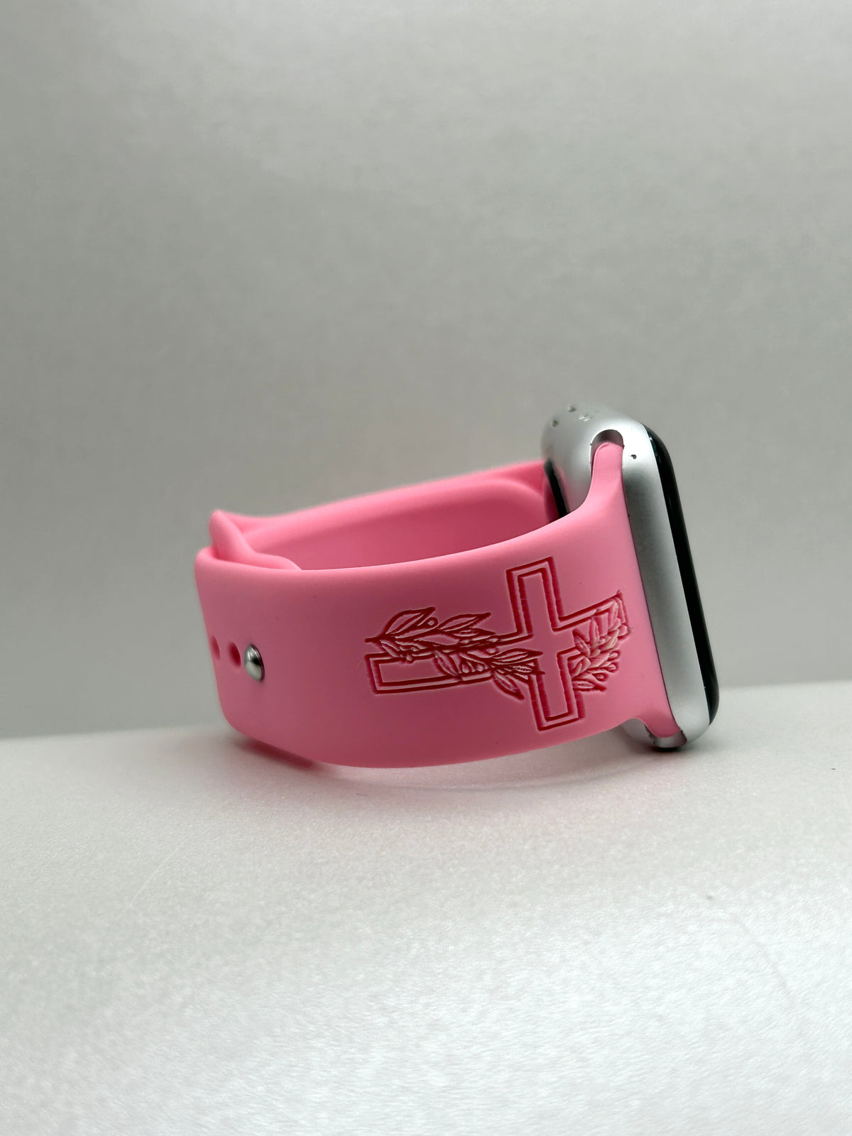 Side view of a pink Faith Makes It Possible watch band for Apple Watch showing the cross engraving