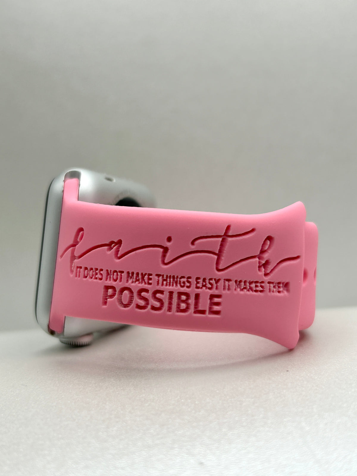 Close-up of the Faith Makes It Possible engraving on a pink watch band for Apple Watch