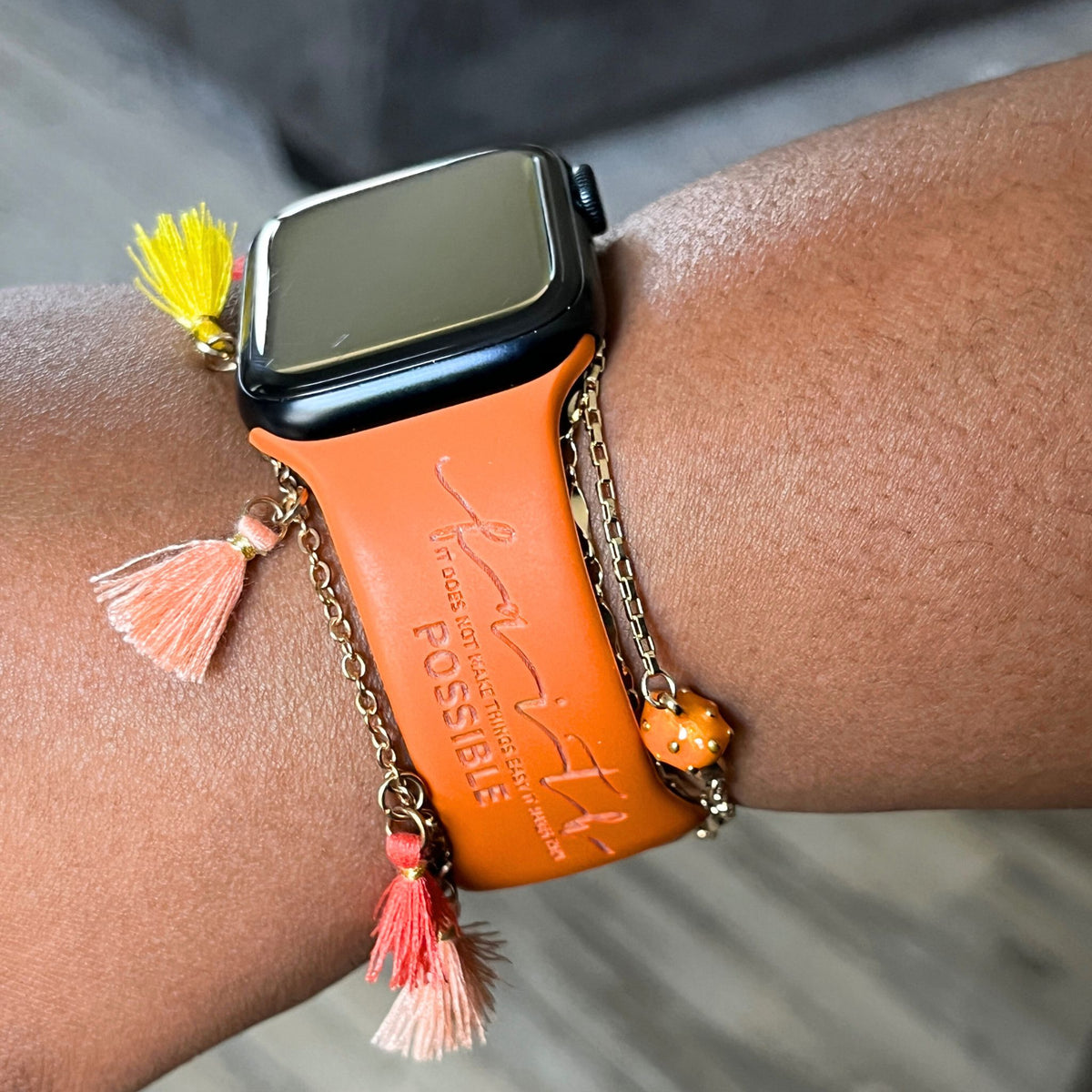 Rust Faith Makes It Possible watch band for Apple Watch worn with a tassel bracelet, watch face view
