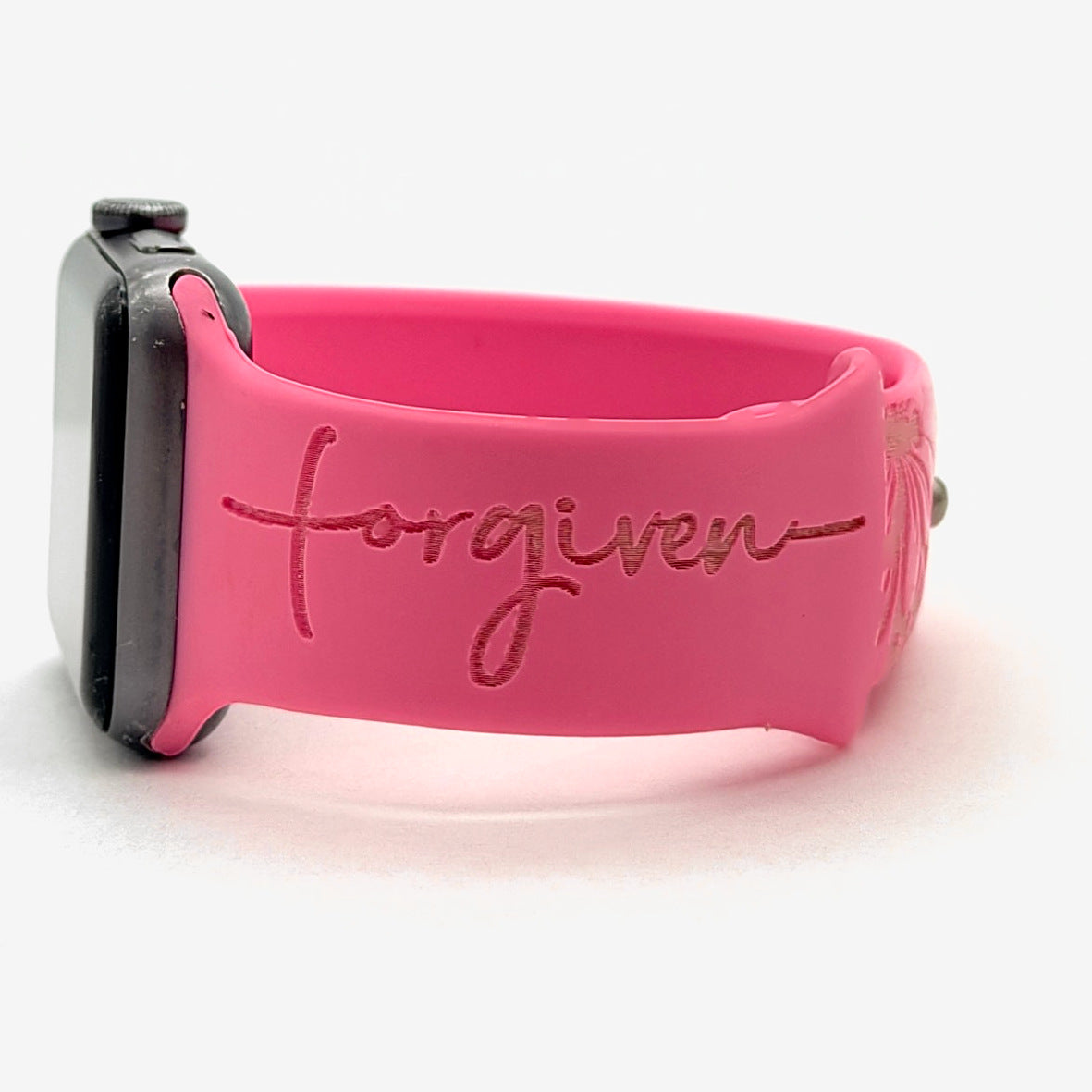 Side view of a pink watch band for Apple Watch engraved with the word Forgiven