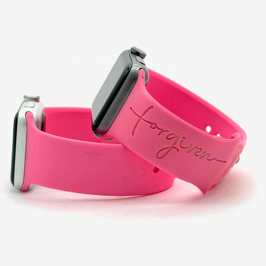 Pink Forgiven watch band for Apple Watch with a cross-style script engraving, shown as a pair