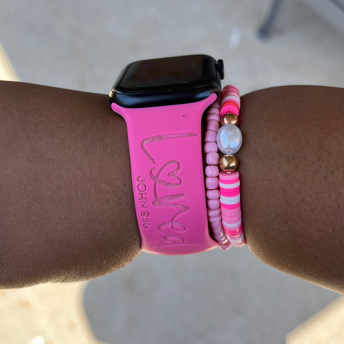 Close-up of the Loved John 3:16 engraving on a hot pink watch band for Apple Watch, worn on a wrist