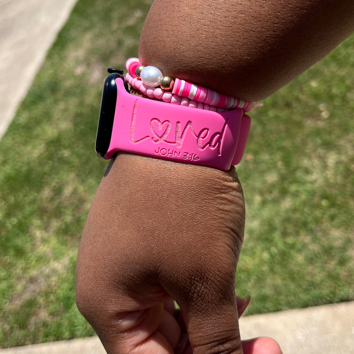 Hot pink Loved John 3:16 watch band for Apple Watch worn on a wrist with pink beaded bracelets