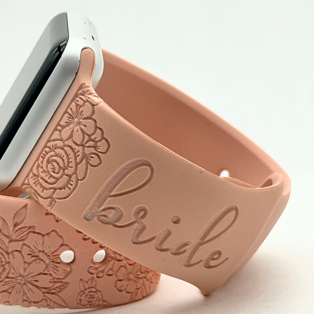 Close-up of the bride script and floral engraving on a blush silicone watch band for Apple Watch