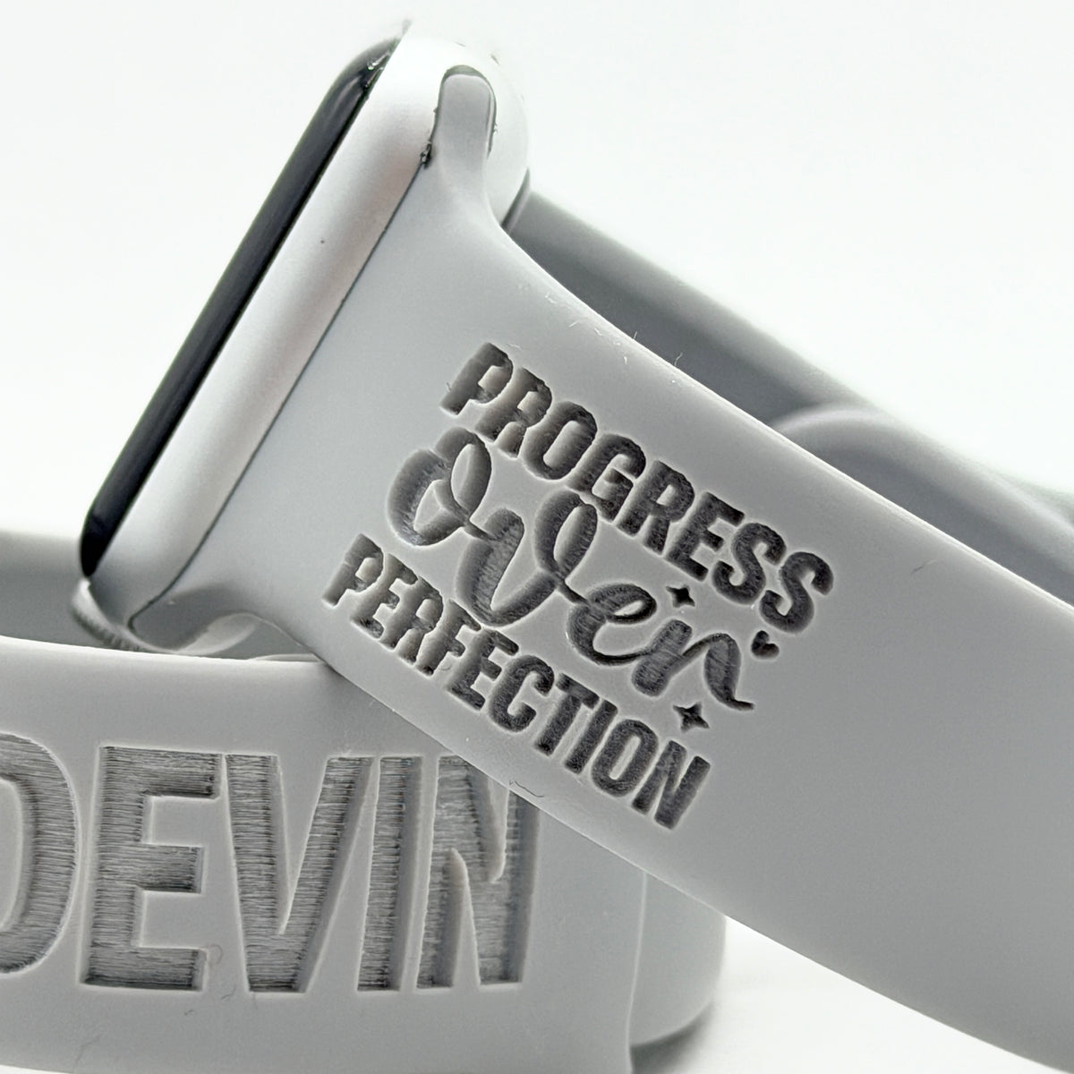 Close-up of the Progress Over Perfection Bold engraving on a grey Progress Over Perfection watch band for Apple Watch