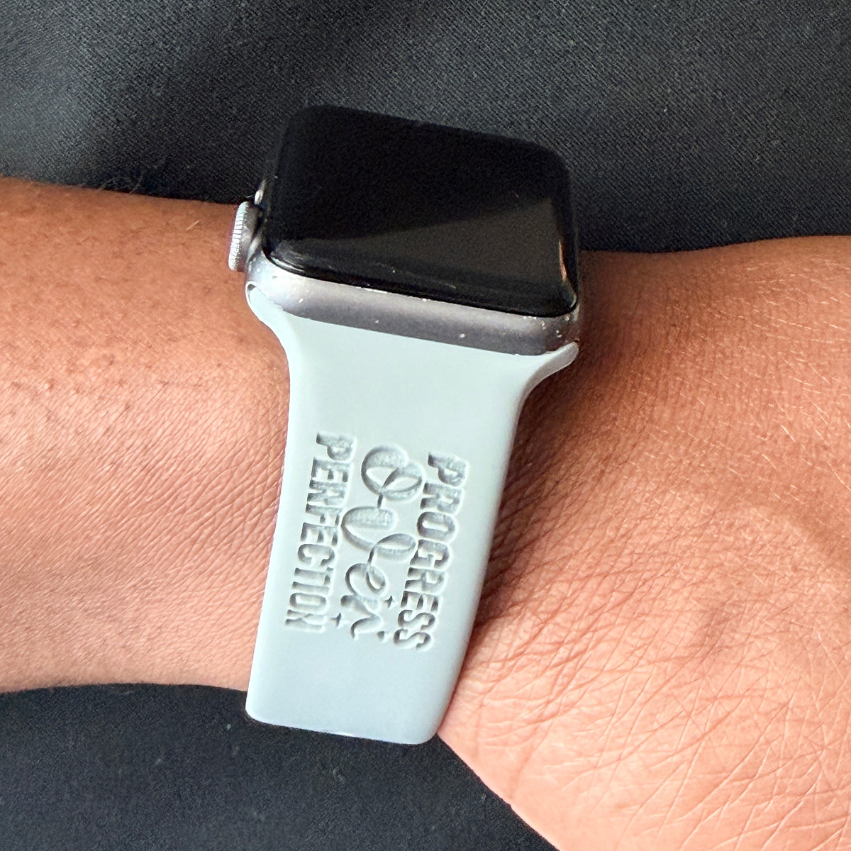 Progress Over Perfection watch band for Apple Watch in grey with the Progress Over Perfection engraving, styled on a wrist