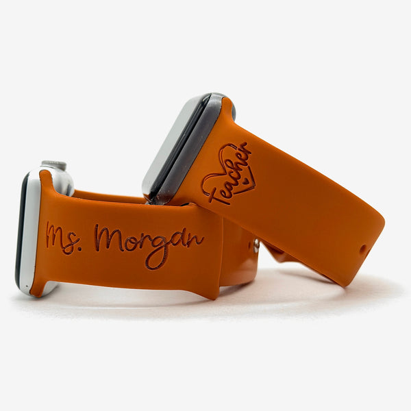 Rust Teacher watch band for Apple Watch engraved with the Teacher Heart Outline design, shown with a band engraved with the name Ms. Morgan